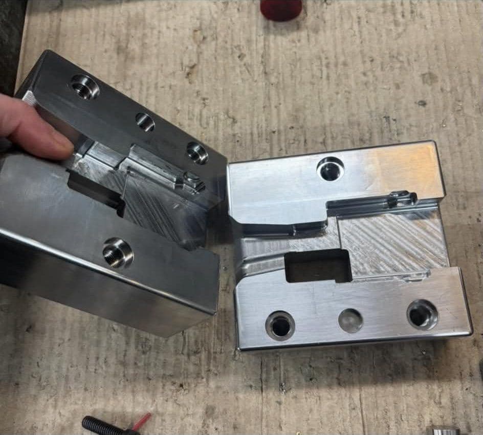 Two mating machined blocks with pocketed detail and fitted inserts, on the bench.